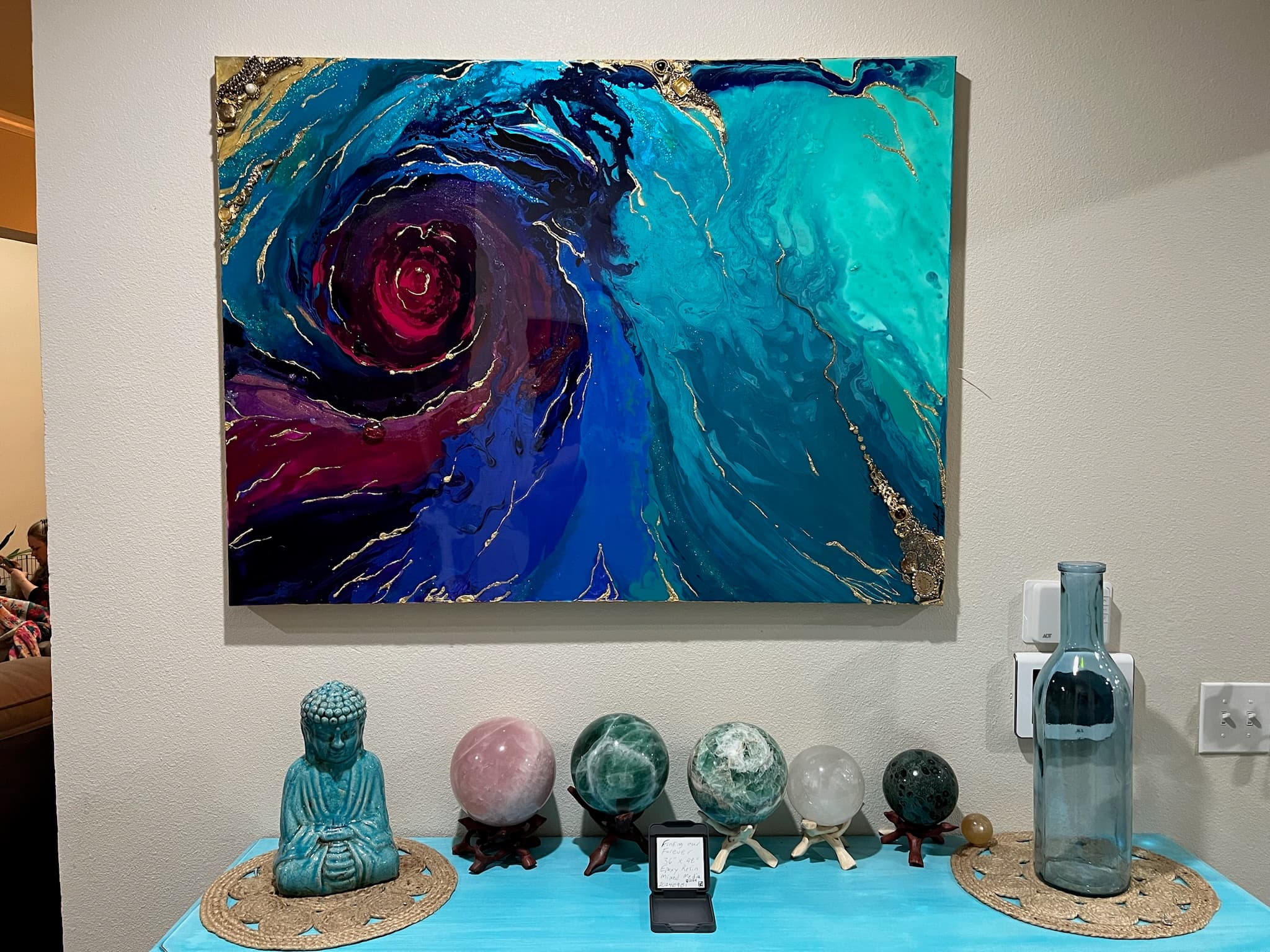 Finding Forever displayed on a wall, with a deep blue and turquoise swirl around burgundy and magenta.